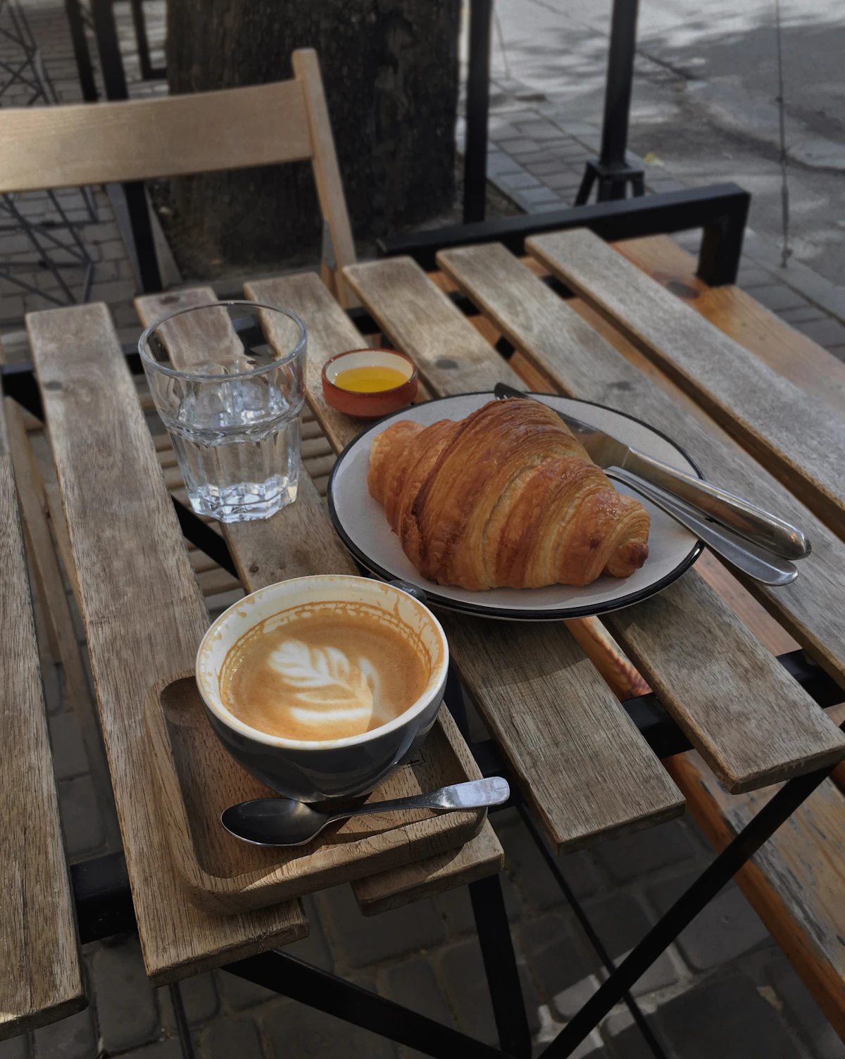 Café con arte latte y croissant en una mesa al aire libre